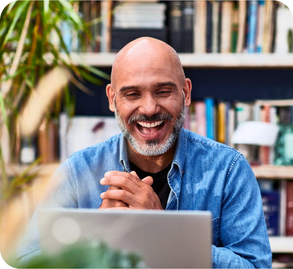 A man with a smile looking at the laptop screen