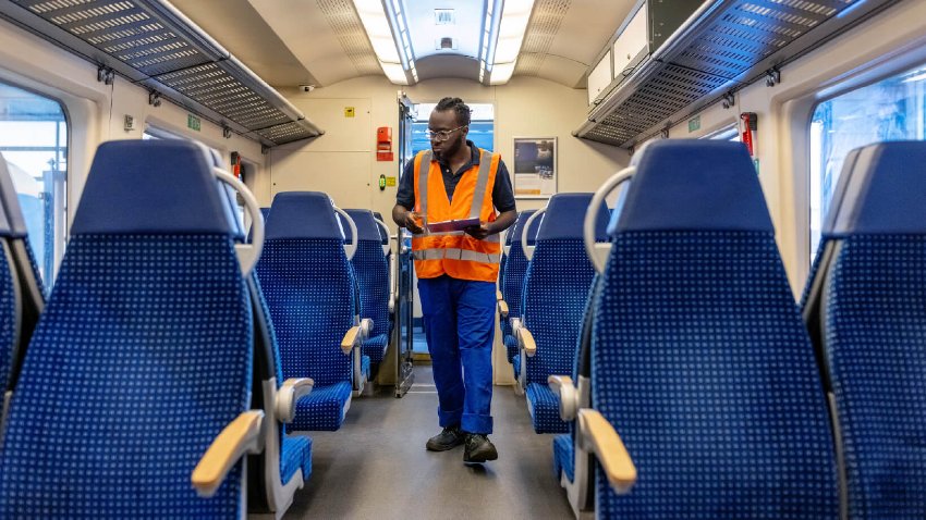 Male engineer checking train carriage interior at railway workshop