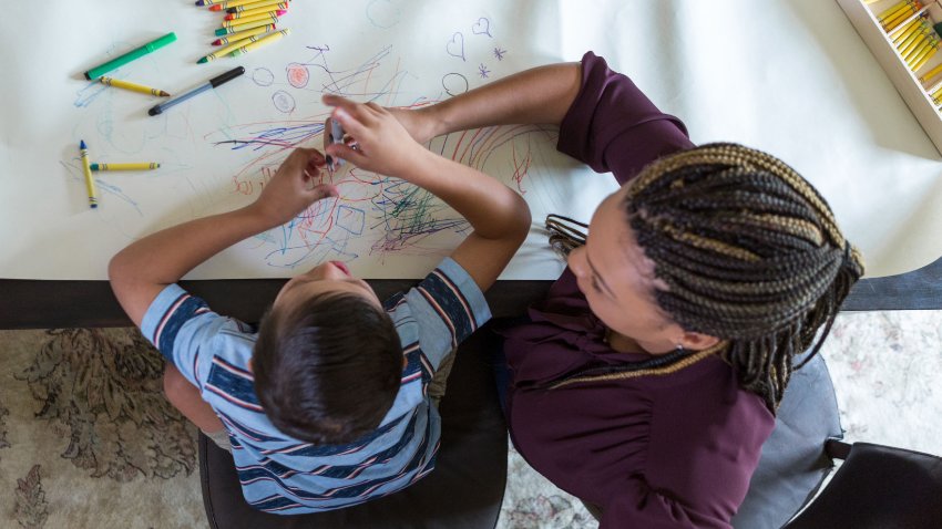 Play therapist colors with boy with Down Syndrome