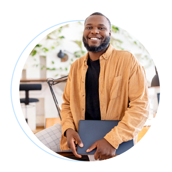 A happy man holding a laptop at work place