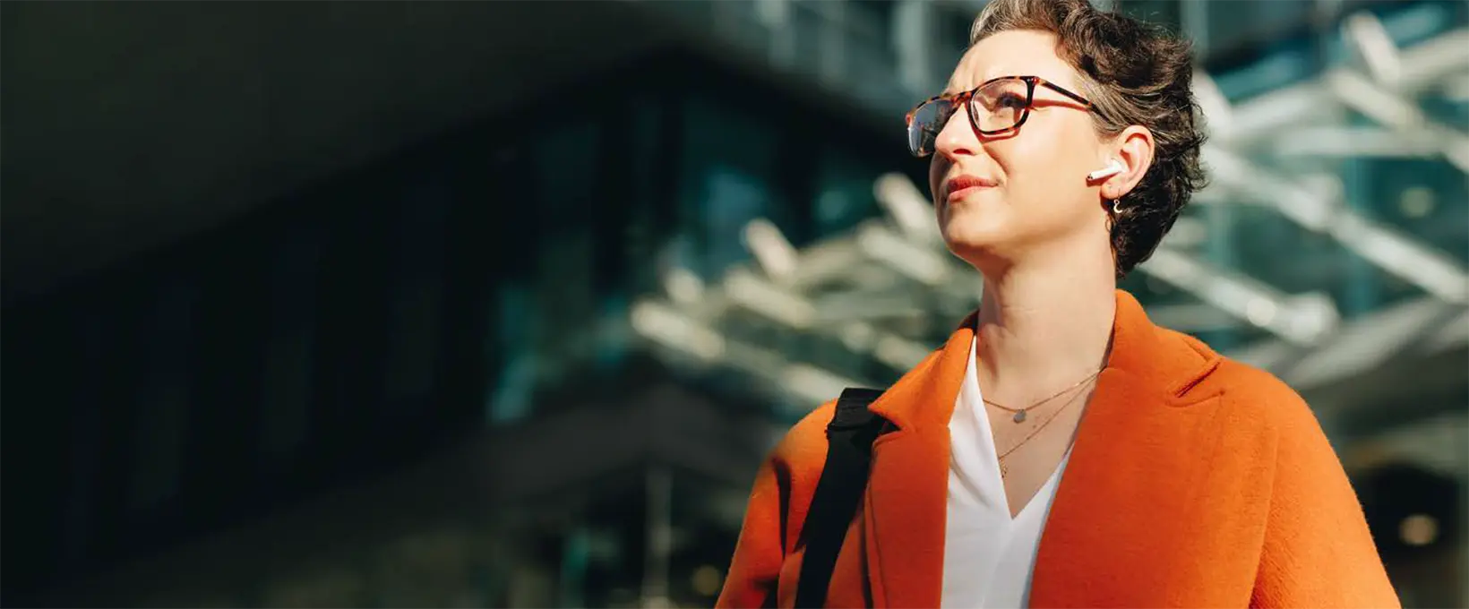 Woman in orange blazer gazing at office building