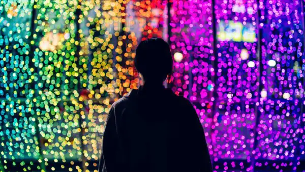 person silhoutted against multicolored lights