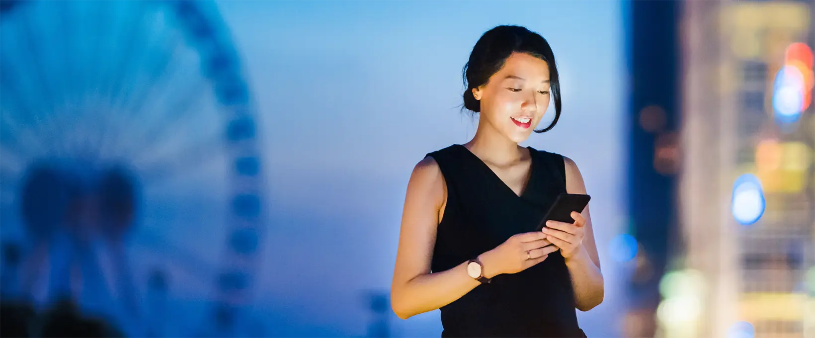 Woman dressed in formal attire smiling while looking at her phone