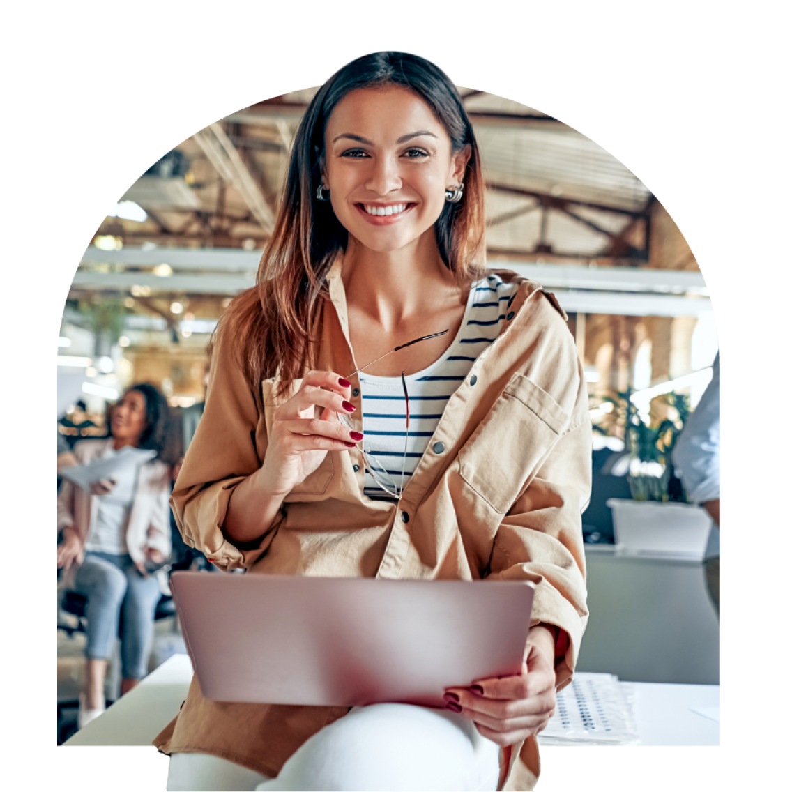 A happy woman holding a laptop at work place